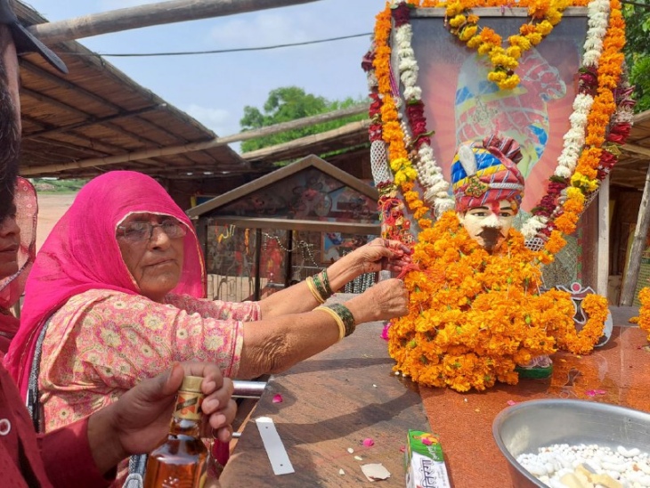 ओम बन्ना की तस्वीर पर राखी बांधते हुए महिला।