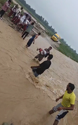 यूपी के सहारनपुर की बरसाती नदी में उफान पर है। नदी पार करते लोग।
