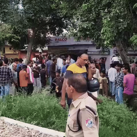 Crowds of people gathered near the railway track.