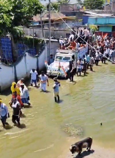 जवान को ला रही गाड़ी पानी में फंस गई। घुटने तक पानी में हाथ में तिरंगा लिए लोग।
