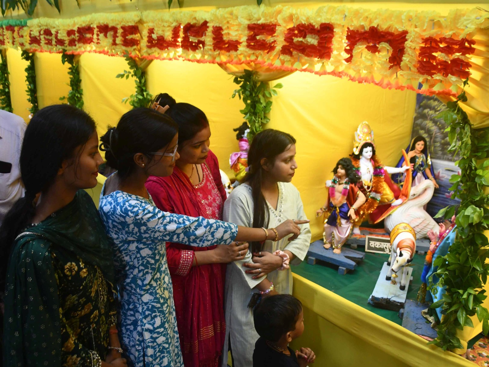 शहर के गलियों में सजे कृष्ण जन्माष्टमी के झांकी को देखती महिलाएं।