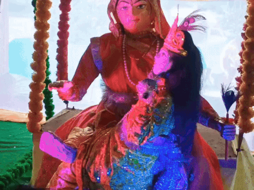 मां यशोदा श्री कृष्ण को झुला झुलाते हुई।