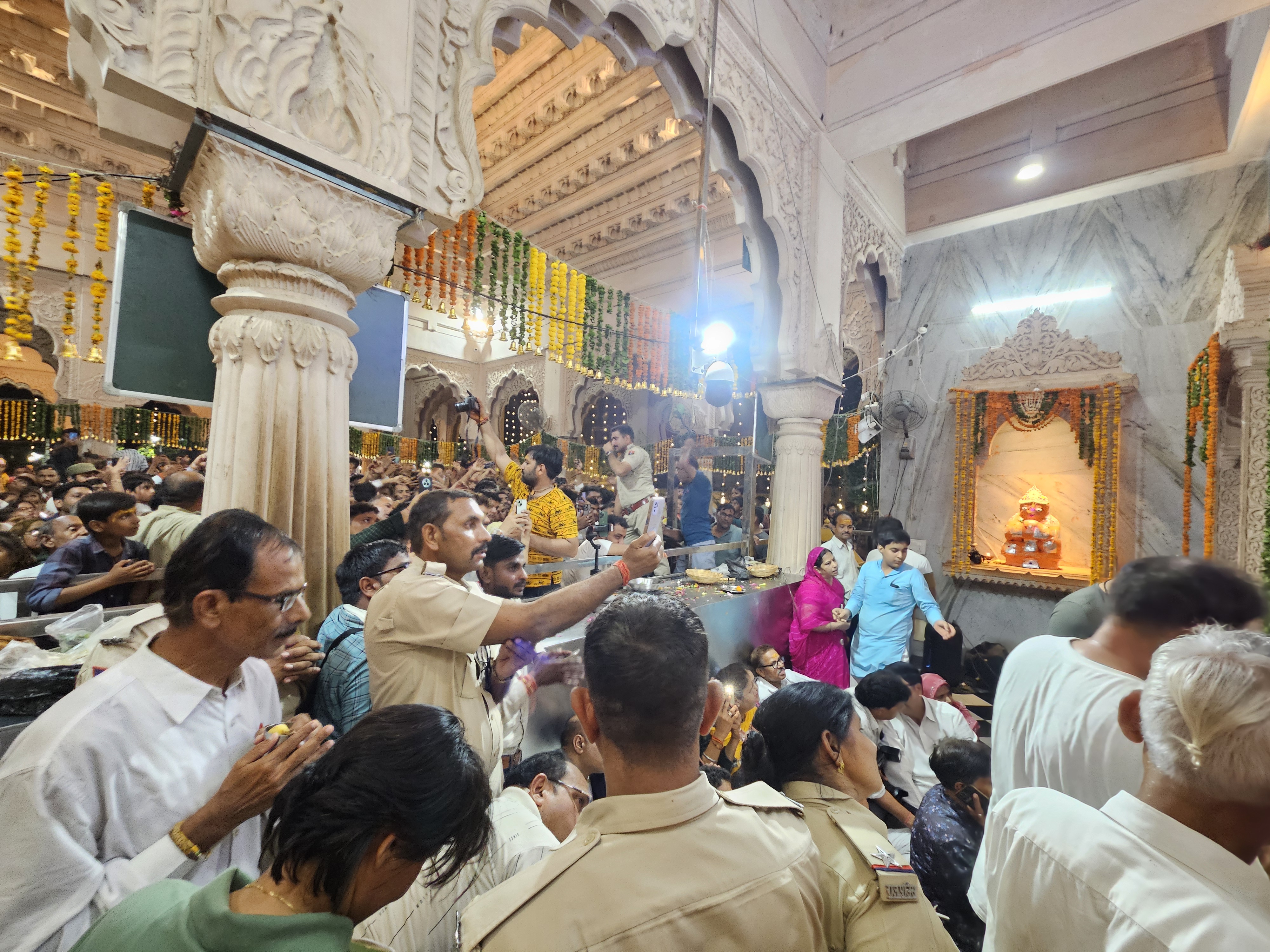 भगवान श्री कृष्ण के अभिषेक के दौरान श्रद्धालुओं को संभालता पुलिसकर्मी।