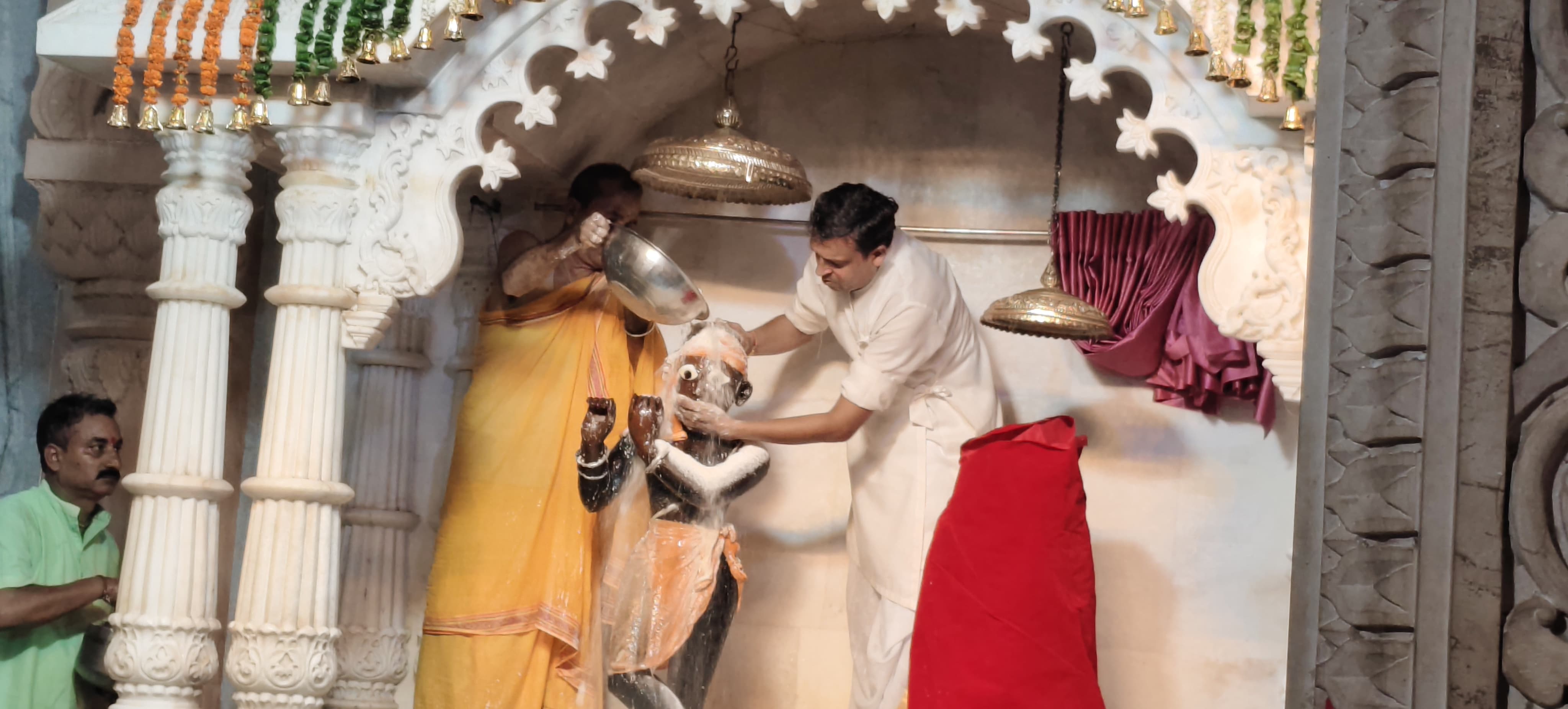 भगवान श्री कृष्ण का दूध और दही से अभिषेक करते मंदिर के पुजारी।