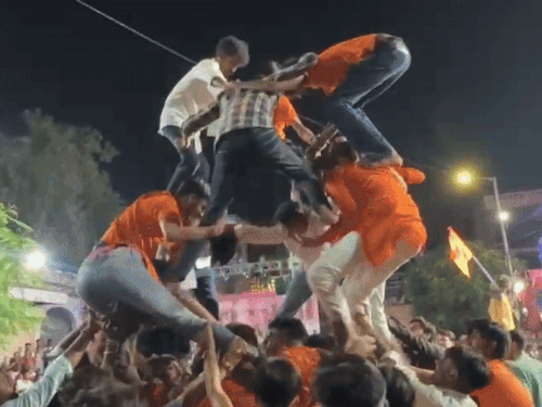 कल्याण मंदिर के बाहर मटकी फोड़ प्रतियोगिता के दौरान नीचे गिरते हुए बजरंग दल के कार्यकर्ता।