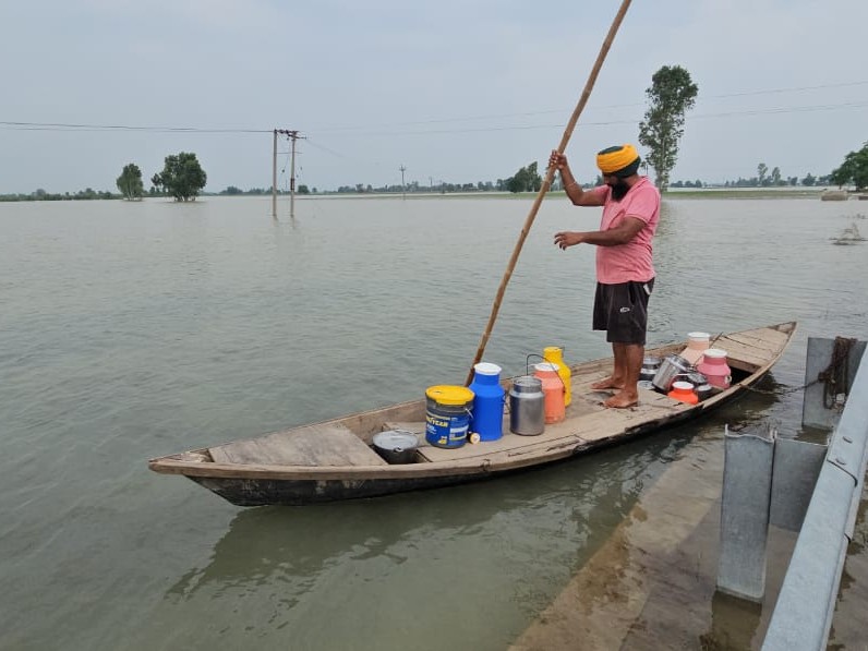 नाव पर राहत सामग्री लेकर जाता ग्रामीण युवक।