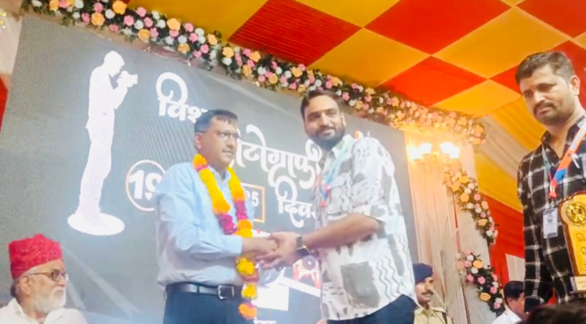 जिला कलेक्टर का माला पहनाकर सम्मान करते हुए फोटोग्राफर।