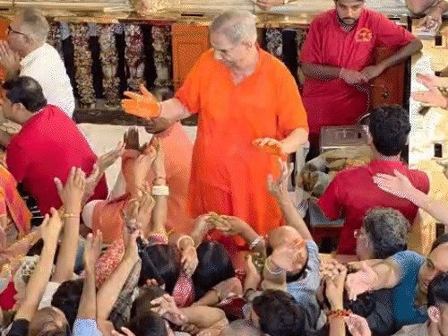 मंदिर महंत कैलाश शर्मा भक्तों को प्रसाद बांटते हुए।