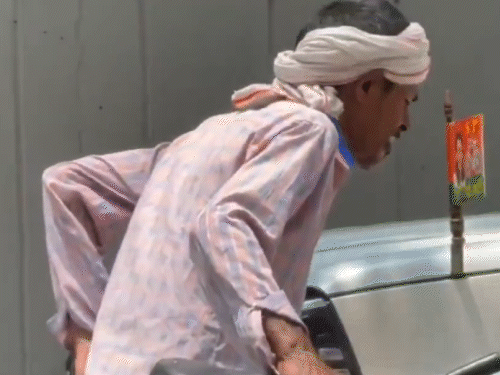 कार के बोनट पर लगे सपा के झंडे को चूमता रिक्शा चालक।