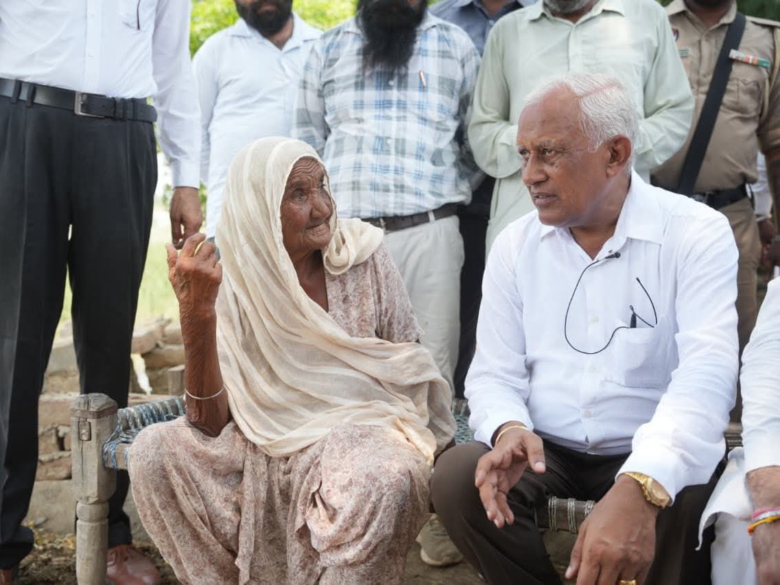 बुजुर्ग महिला से बातचीत करते मंत्री।