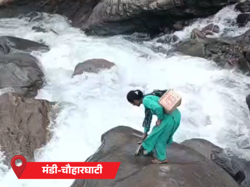Kamla taking off the shoes before leaping on a splashing drain in Mandi's Chauharghati