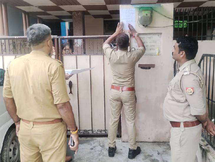 आरोपियों के घर नोटिस चस्पा करती पुलिस
