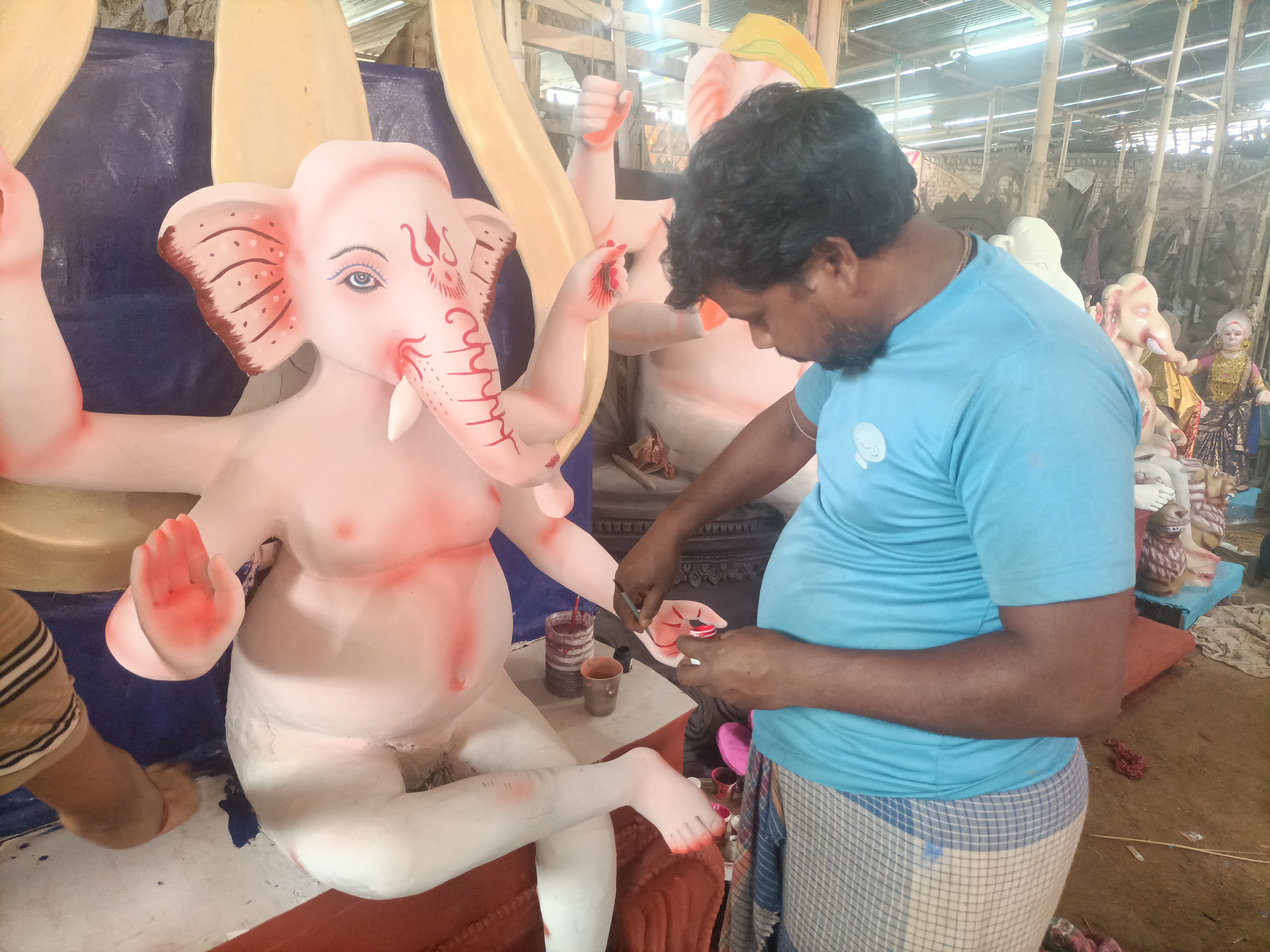 मिट्टी से बनाई जा रही गणेश प्रतिमा पर अंतिम नक्काशी करते मूर्तिकार बलराम।