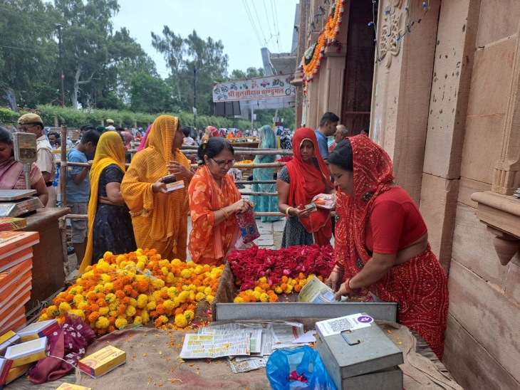 नागा बाबा बगेची के बाहर श्रद्धालु फूलों की माला खरीदते हुए।
