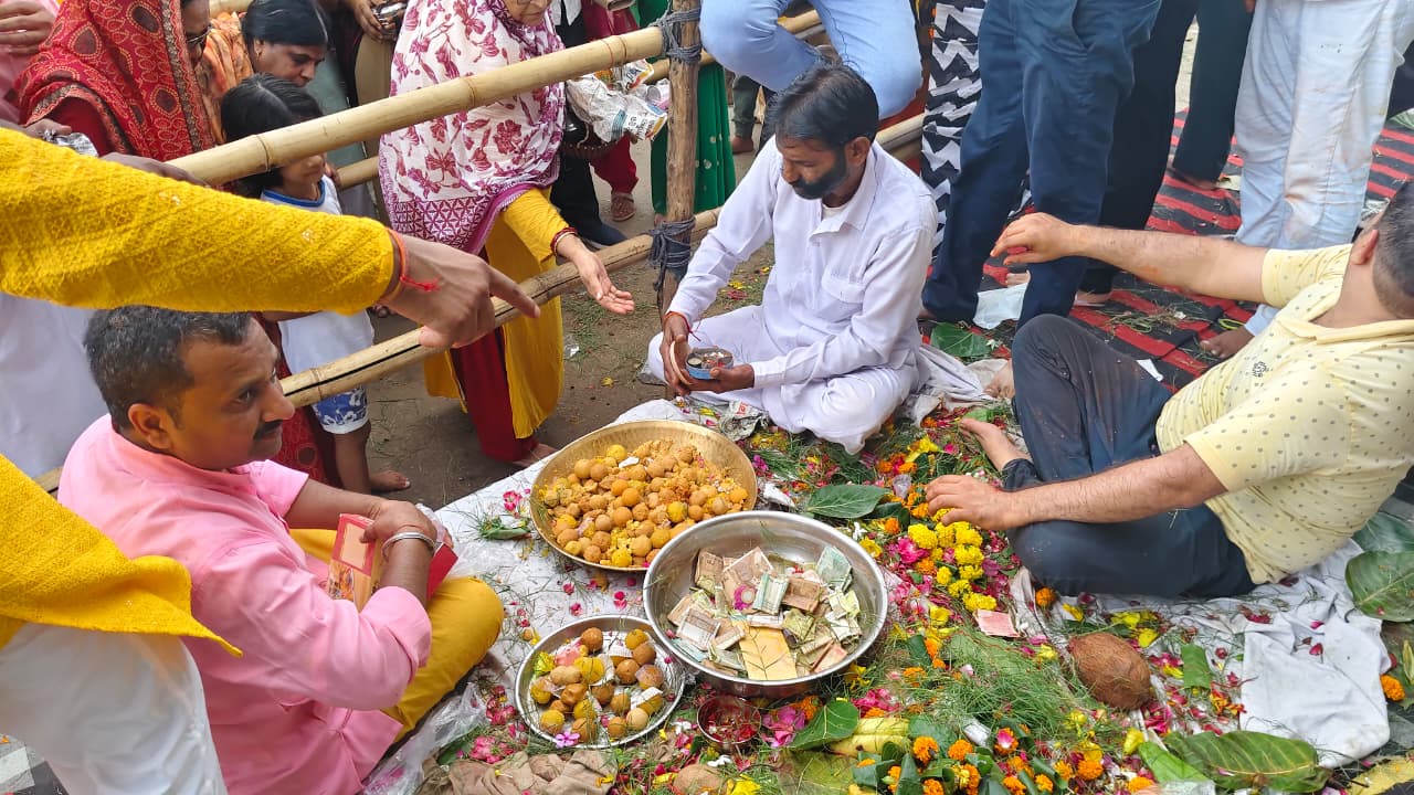 गणेश मंदिर के पुजारी श्रद्धालुओं को बेसन के लड्डुओं का प्रसाद देते हुए।