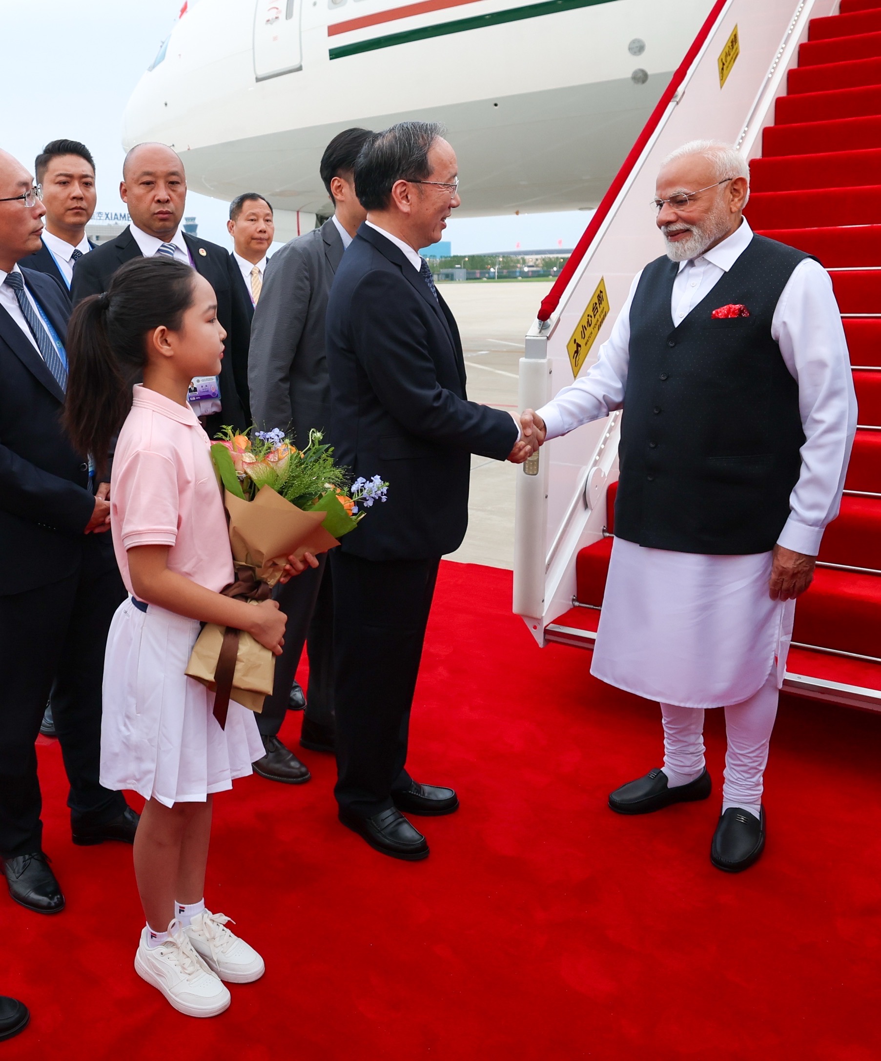 एयरपोर्ट पर चीन की एक बच्ची पीएम मोदी को गुलदस्ता देकर उनका स्वागत करते हुए।