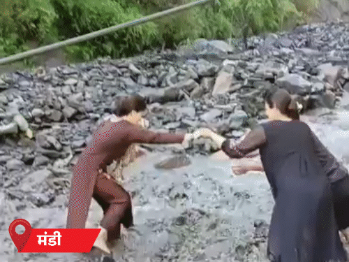 Teacher crossing the swollen drain in Balichowki of Mandi.