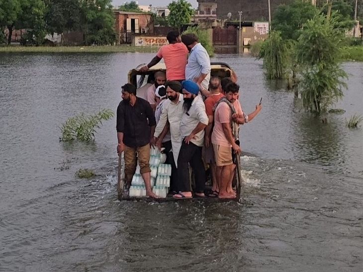 पंजाब के होशियारपुर में डेरा बाबा नानक एरिया में बाढ़ आई है। प्रभावित लोगों के लिए पीने वाला पानी और अन्य सामान लेकर जाते हुए लोग।