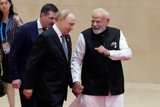 मंच पर हाथ पकड़ कर चलते हुए नजर आए पुतिन और मोदी।
