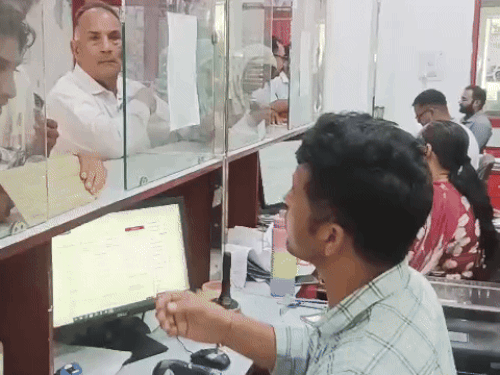 लोगों को डाक सेवाएं उपलब्ध करवाते कर्मचारी
