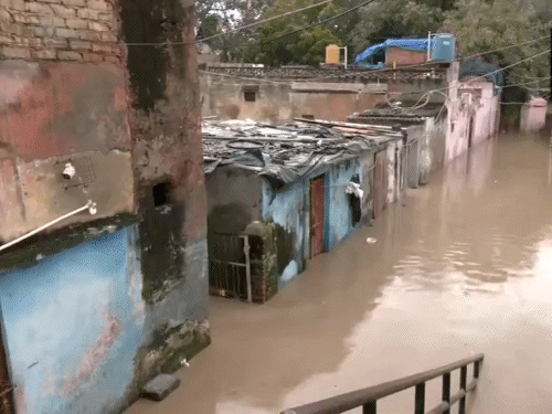 यमुना बाजार इलाके में करीब 3 फीट तक पानी भरा। गहरे पानी से होकर गुजरते लोग।