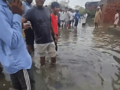 गांव मिर्जापुर में गली में घुटनों तक खड़े पानी को दिखाते लोग।