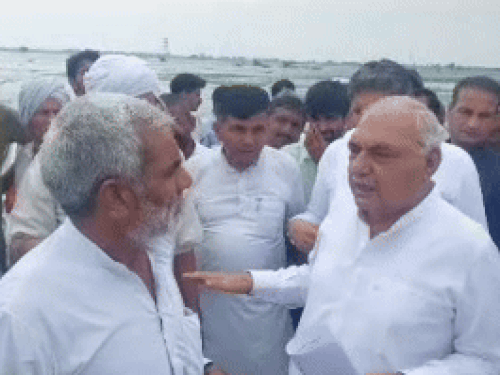 Bhupendra Hooda talking to people about waterlogging in the fields of village Paksma.