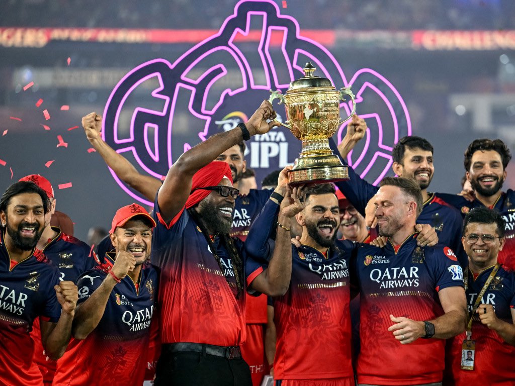 RCB की IPL जीत के दौरान ट्रॉफी के साथ क्रिस गेल (पगड़ी पहने हुए), विराट कोहली (बीच में), एबी डिविलियर्स (दाएं) और RCB के बाकी प्लेयर्स।