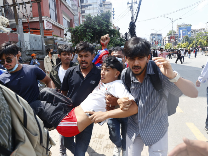 पुलिस की गोलीबारी से घायल हुए युवक को इलाज के लिए ले जाते प्रदर्शनकारी।