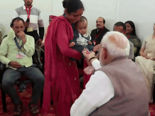 बाढ़ में अपने माता-पिता और दादी को खो चुकी एक साल की नितिका को प्रधानमंत्री नरेंद्र मोदी ने टॉफी दी।