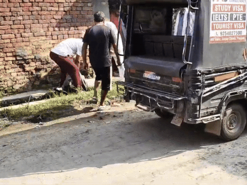 अधेड़ के शव को नाले से निकालते ग्रामीण।