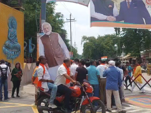 भाजपा कार्यकर्ता PM मोदी का कटआउट कार्यक्रम स्थल पर लगाने के लिए ले जाते हुए।