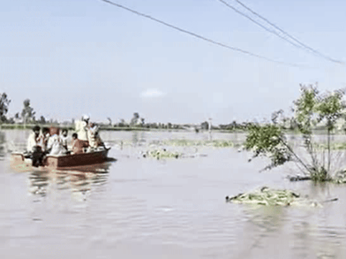 बाढ़ दौरान किश्ती में बैठकर जाते लोग।