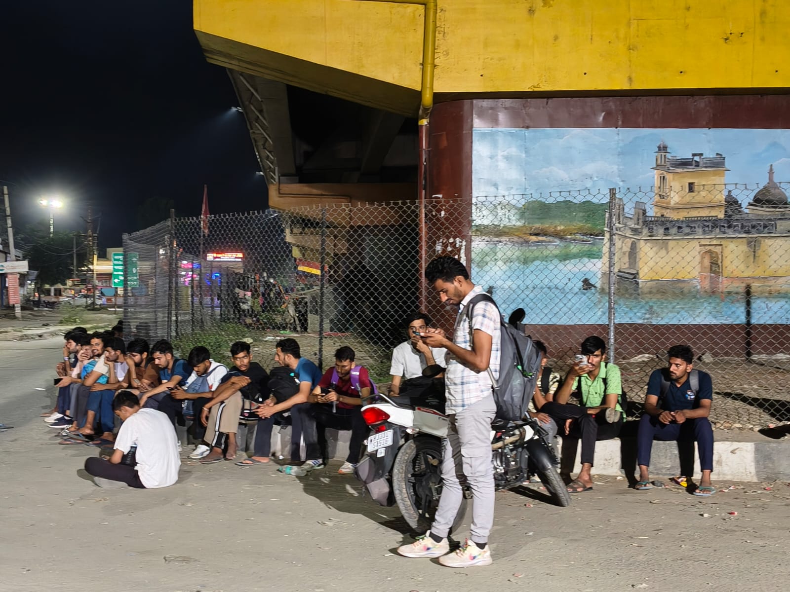 राजनगर बस स्टेंड पर ब्रिज के नीचे बस का इंतजार करते अभ्यर्थी।