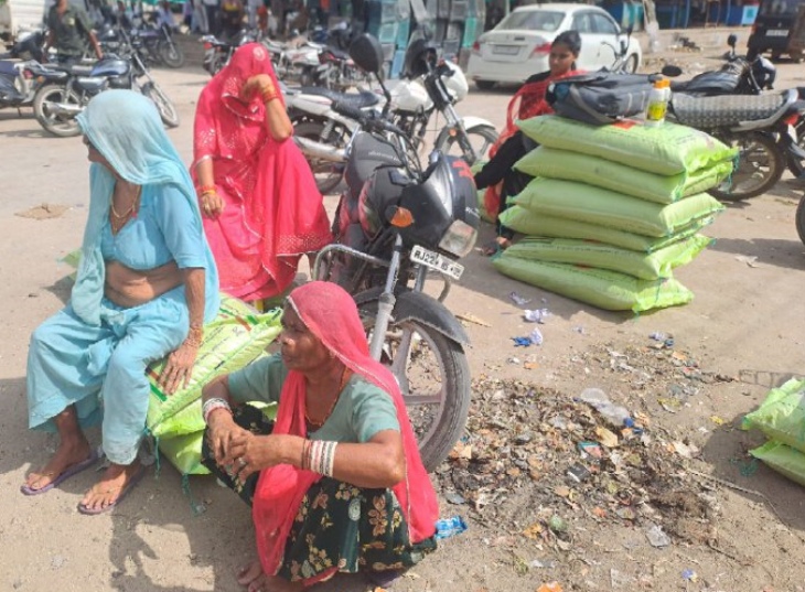 पाली शहर के नई सब्जी मंडी परिसर में क्रय-विक्रय सहकारी समिति में डीएपी खाद के लिए धूप में बैठी महिलाएं।