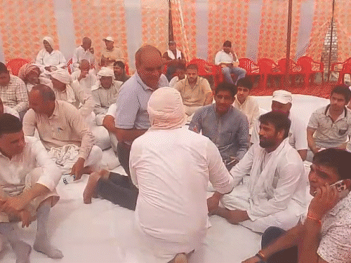 Bajrang sitting among the people, Mahavir Phogat and Arya Virendra Singh and Harendra Poonia talking about their father.