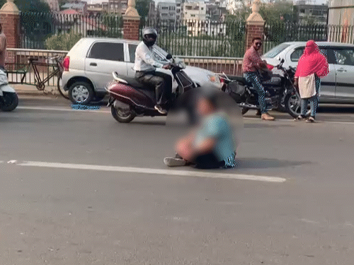 सूरसागर तालाब के सामने बीच सड़क पर बैठी महिला।