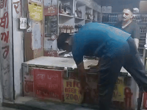 शराब के ठेके के बाहर पानी, खाना और नमकीन के लगे पोस्टर उतारते ठेके के करिंदे।