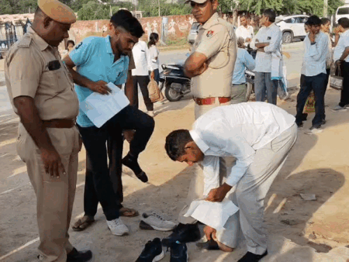 जूते पहनकर आए अभ्यर्थियों के जूते खुलवाते हुए पुलिस के जवान।