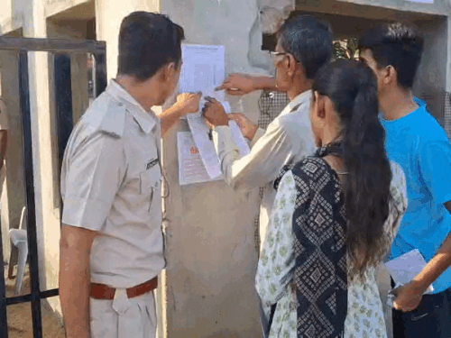 सेंटर के बाहर अपने रोल नंबर देखते कैंडिडेट।