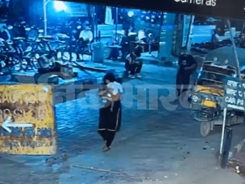 बच्चे को किडनैप करके काले सूट में ले जाती महिला।