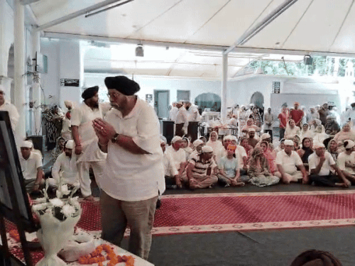 रिच्ची केपी की तस्वीर के आगे नमस्कार करते हुए लोग।