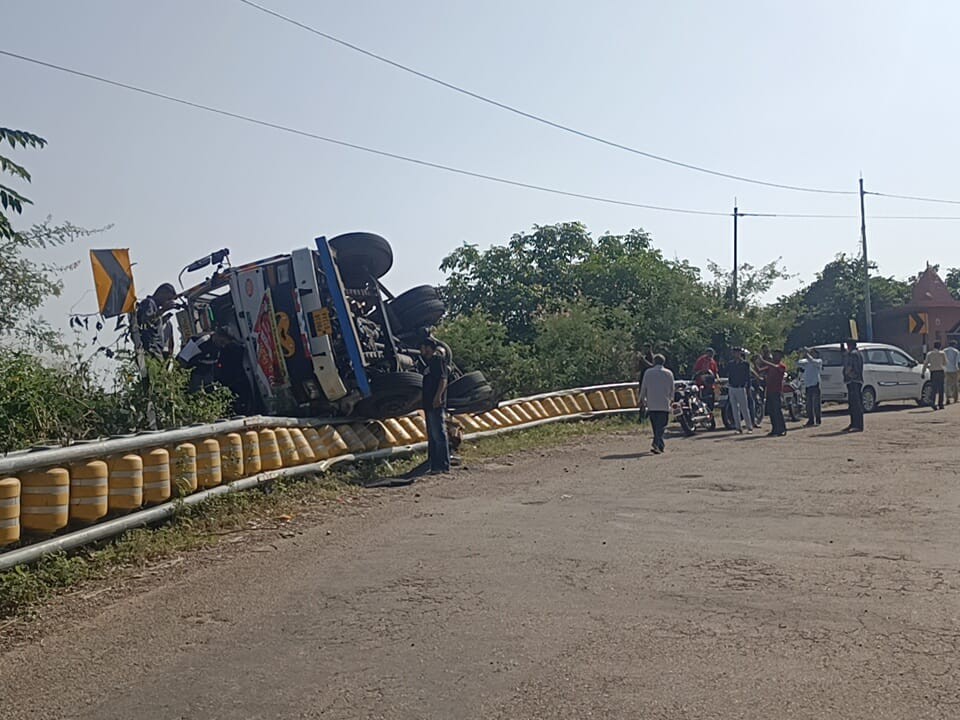 बस की टक्कर के बाद ट्रक रोड के किनारे पलटा है। नीचे खाई में गिरने से बाल बाल बचा है।