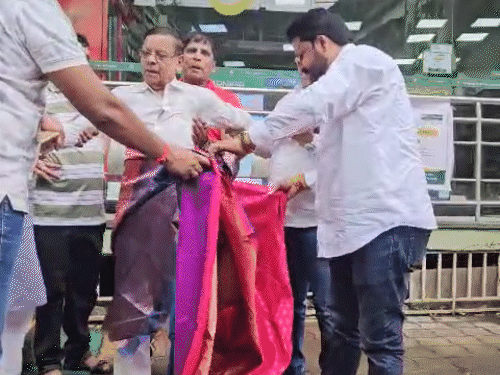 भाजपा कार्यकर्ता पागरे को हाथ पकड़कर जबरदस्ती साड़ी पहनाने लगे।