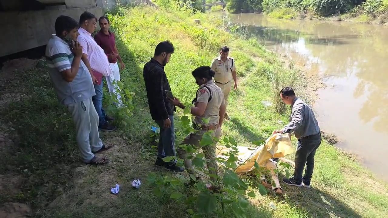 युवती के शव को कब्जे में लेती पुलिस टीम।