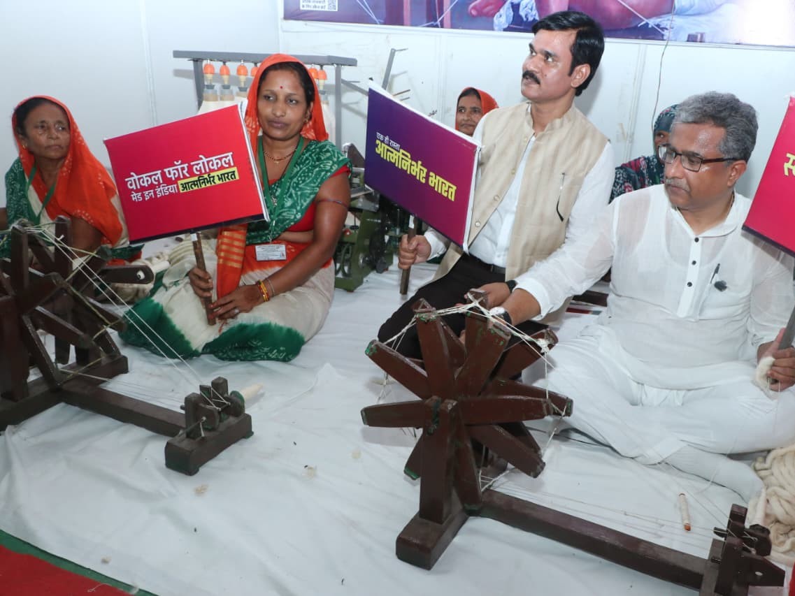 चरखा पर सूत काट रहे लोग।