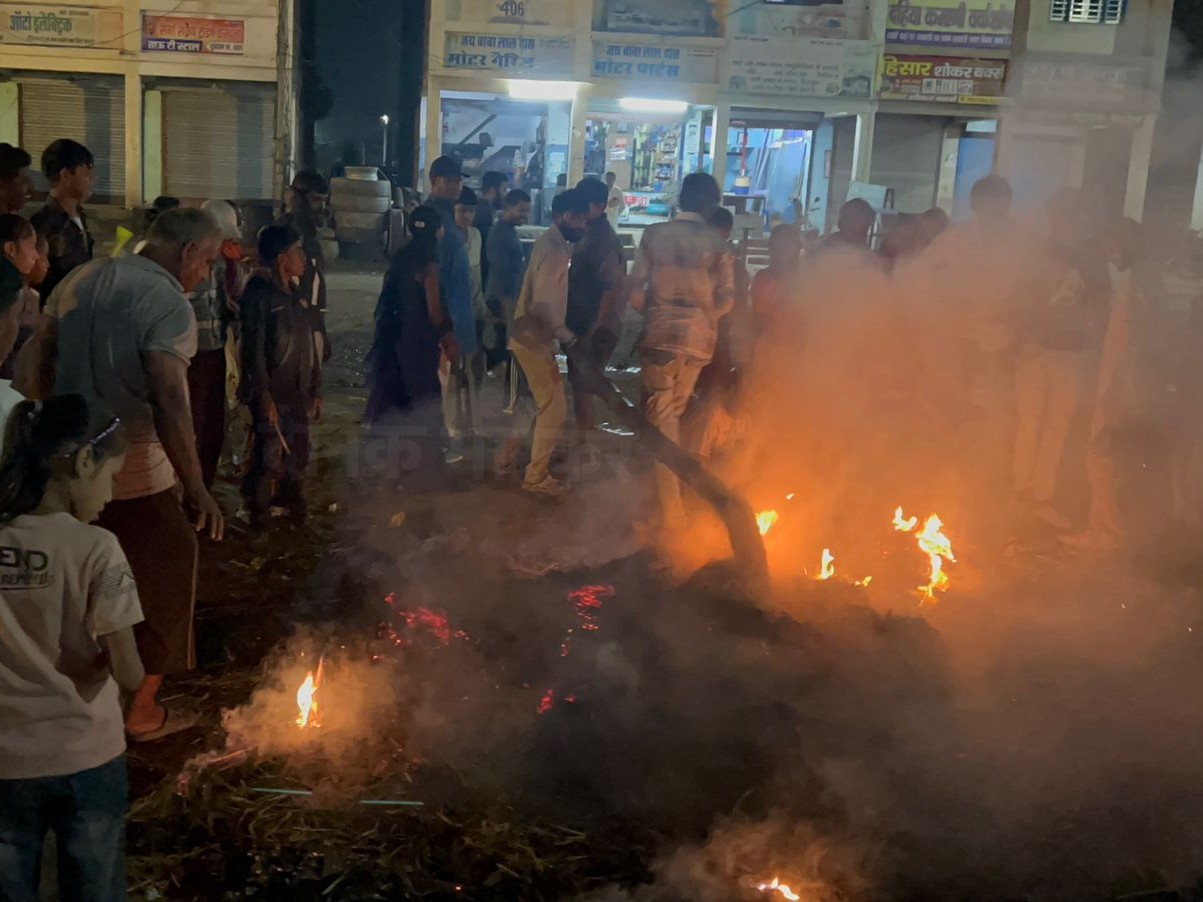 नई ऑटो मार्केट में रावण दहन के बाद जलती लकड़ियां ले जाते लोग।