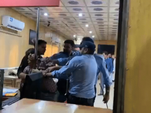 3 पुलिसकर्मी एक पत्रकार को खींचकर ले जाने की कोशिश करते हुए।
