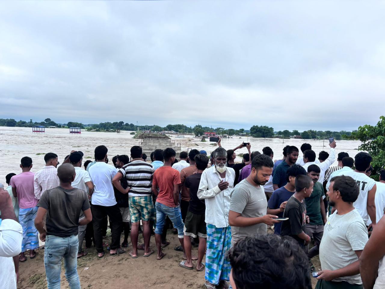 पानी से कटान के बीच ऊंचे स्थान पर मौजूद लोग।