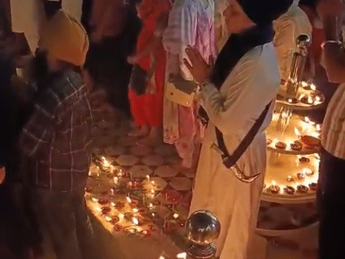 गोल्डन टेंपल में दीए जलाने के बाद अरदास करते हुए श्रद्धालु।